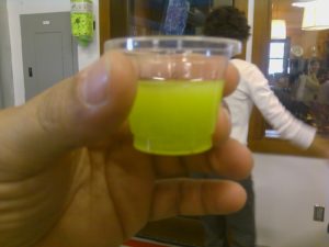 Person holding a small cup of fresh pressed olive oil